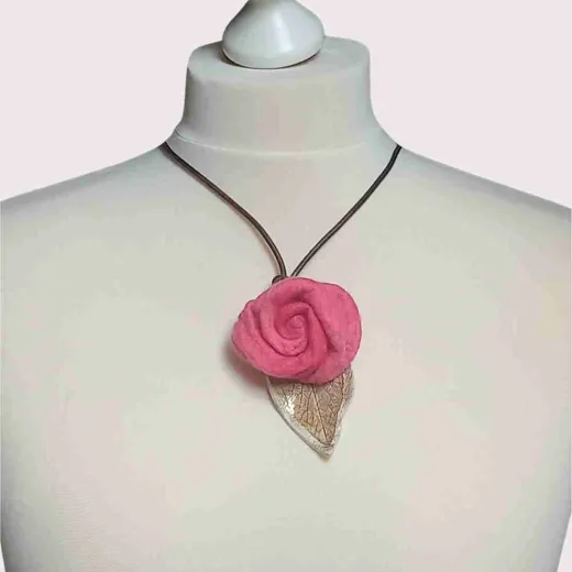 Diese elegante Filzkette verbindet eine lebhafte pinke Filzrose mit einem sanften Keramikblatt in Beigetönen, alles an einem stilvollen braunen Lederband befestigt. Ideal für jede Gelegenheit, bringt sie Farbe und Individualität in dein Outfit. Jedes Det
