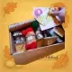 Geöffnete Materialbox, in der eine Hand zwei kleine Filzland-Kärtchen hineinlegt. Sichtbar sind sortierte Wollpäckchen und Zubehör für die Winterprojekte. Persönlicher, handgemachter Eindruck.„Mit Liebe gepackt – von Hand zu Hand.“